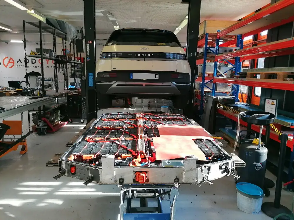 Ioniq 5 na dizalici, ispod njega izvađena baterija s otkrivenim modulima